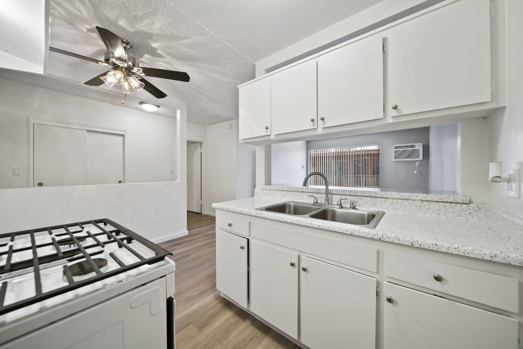 A kitchen with a white stove top oven and white cabinets.