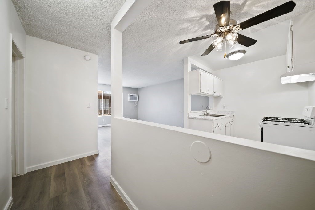 A white room with a ceiling fan and a small kitchenette.