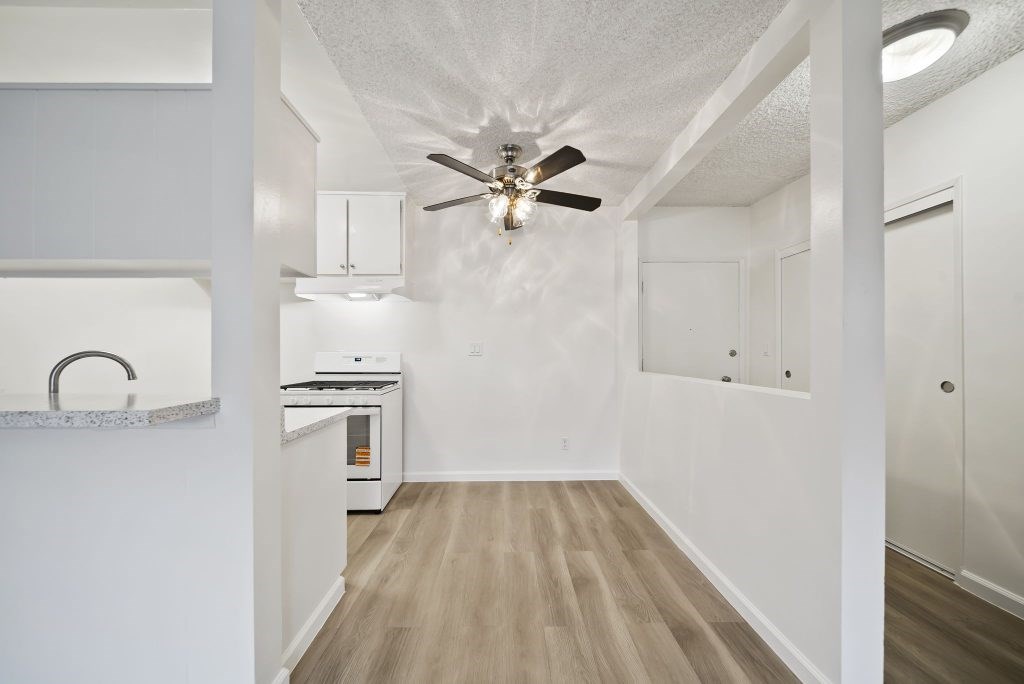 A kitchen with a fan on the ceiling and a counter with a sink.