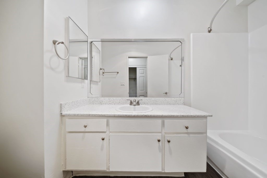 A white bathroom with a sink and a mirror.