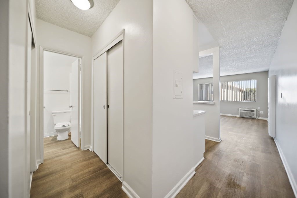 A white bathroom with wood flooring and a toilet.