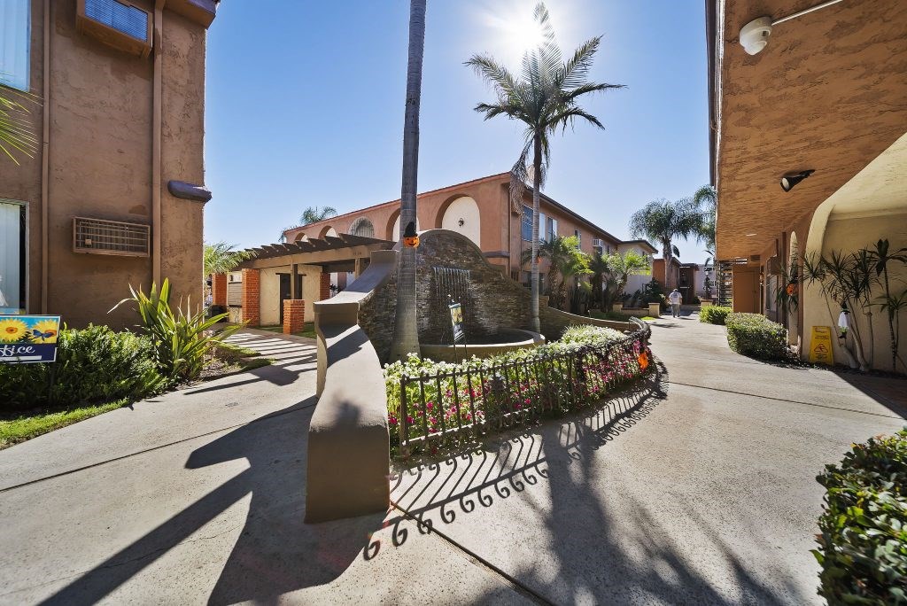 A sunny day in a residential area with a street leading to a house.