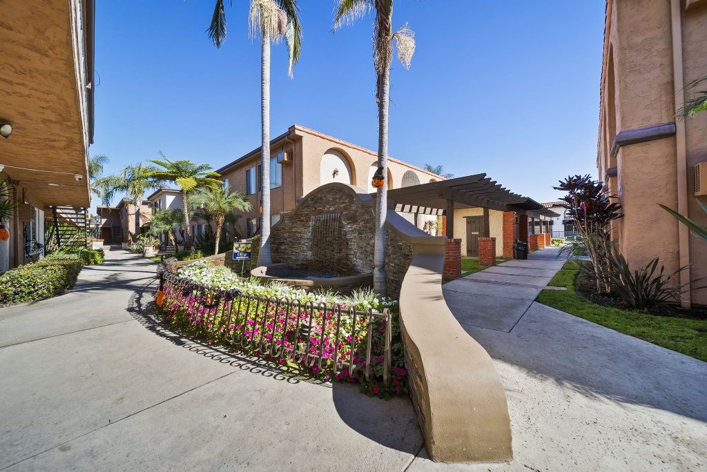 A residential street with houses and a large rock in the middle of the road.