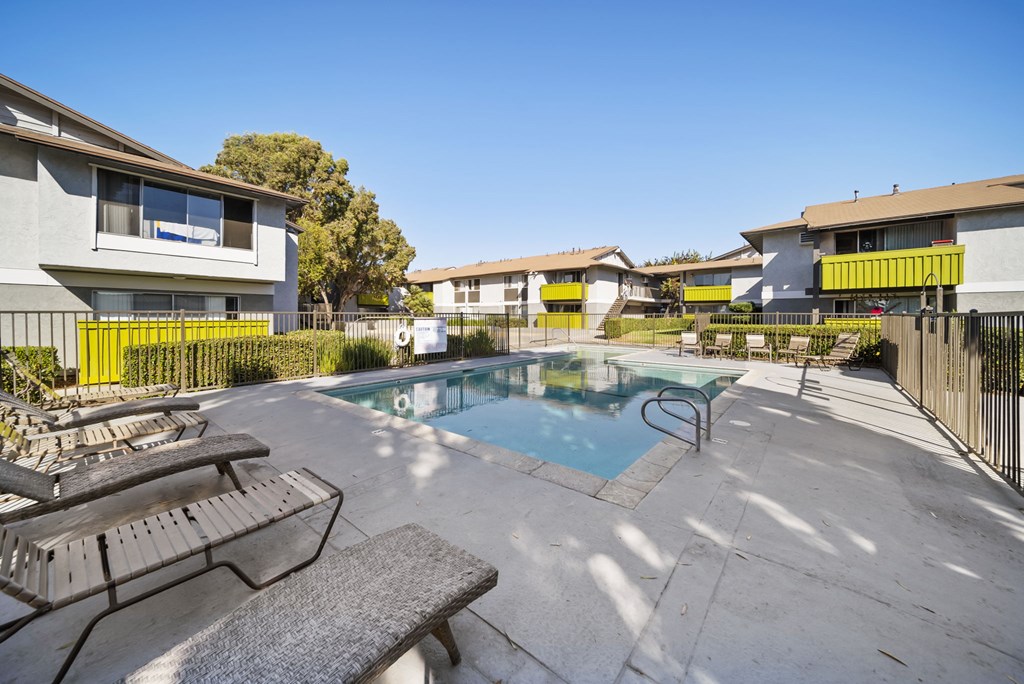 A pool surrounded by a fence and chairs.