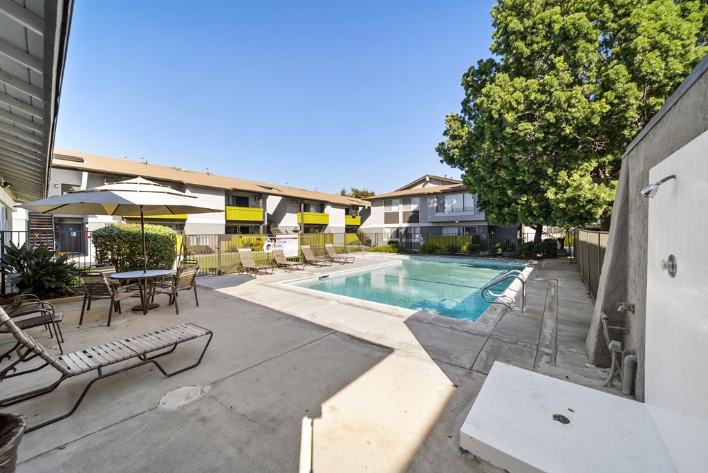 A pool with a table and chairs is surrounded by a concrete patio.