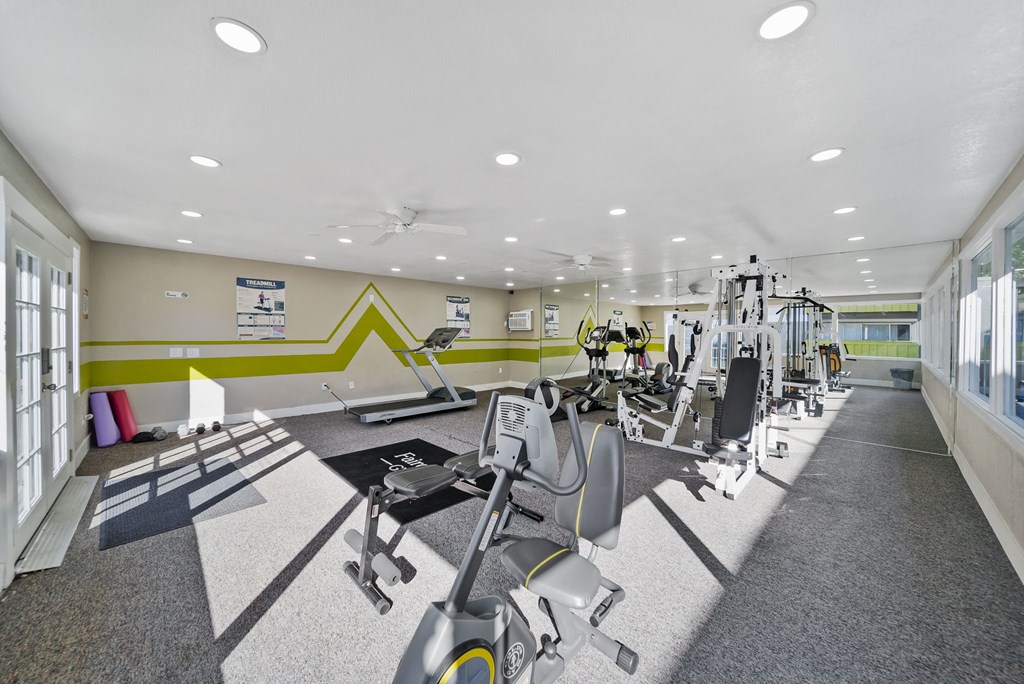 A gym with a variety of equipment including treadmills, weights, and exercise machines.