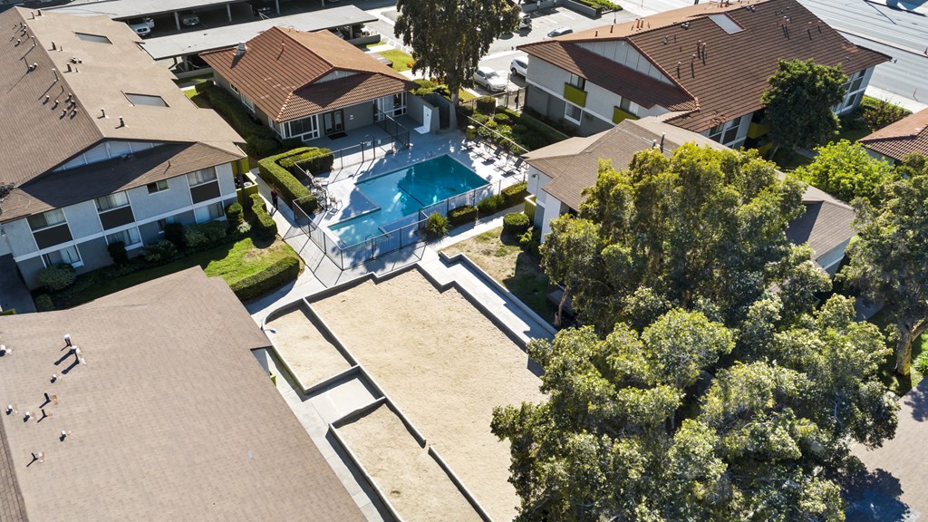 A bird's eye view of a residential area with houses, a swimming pool, and trees.