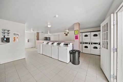 A kitchen with white appliances and a trash can.