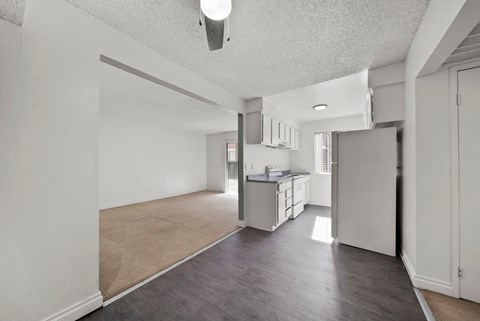 A kitchen area with a refrigerator, sink, and cabinets.