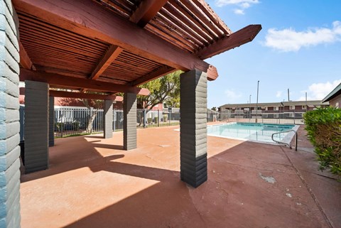 A patio with a pool in the background.