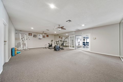 A spacious room with a ceiling fan and exercise equipment.