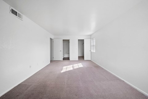 A large empty room with carpeted floor and white walls.