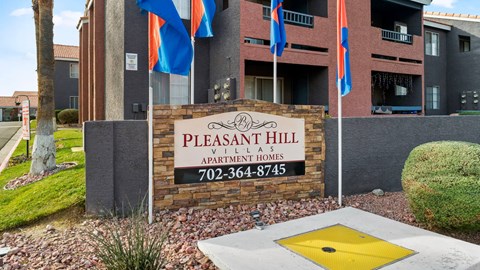 A sign for Pleasant Hill Village Apartments in front of a building.