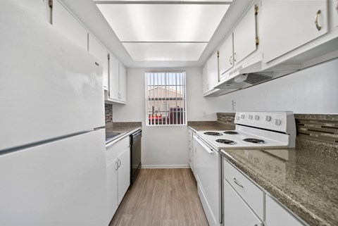A kitchen with white appliances and wooden floors.