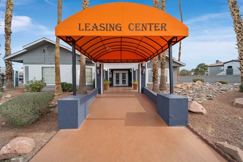 A leasing center with a bright orange canopy and a pathway leading to it.