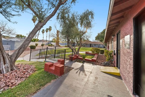 A red brick bench sits in the middle of a concrete walkway.