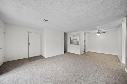 A spacious room with a carpeted floor and a ceiling fan.