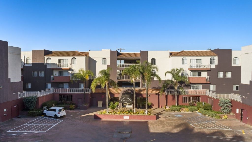 A white car is parked in a parking lot in front of a building.