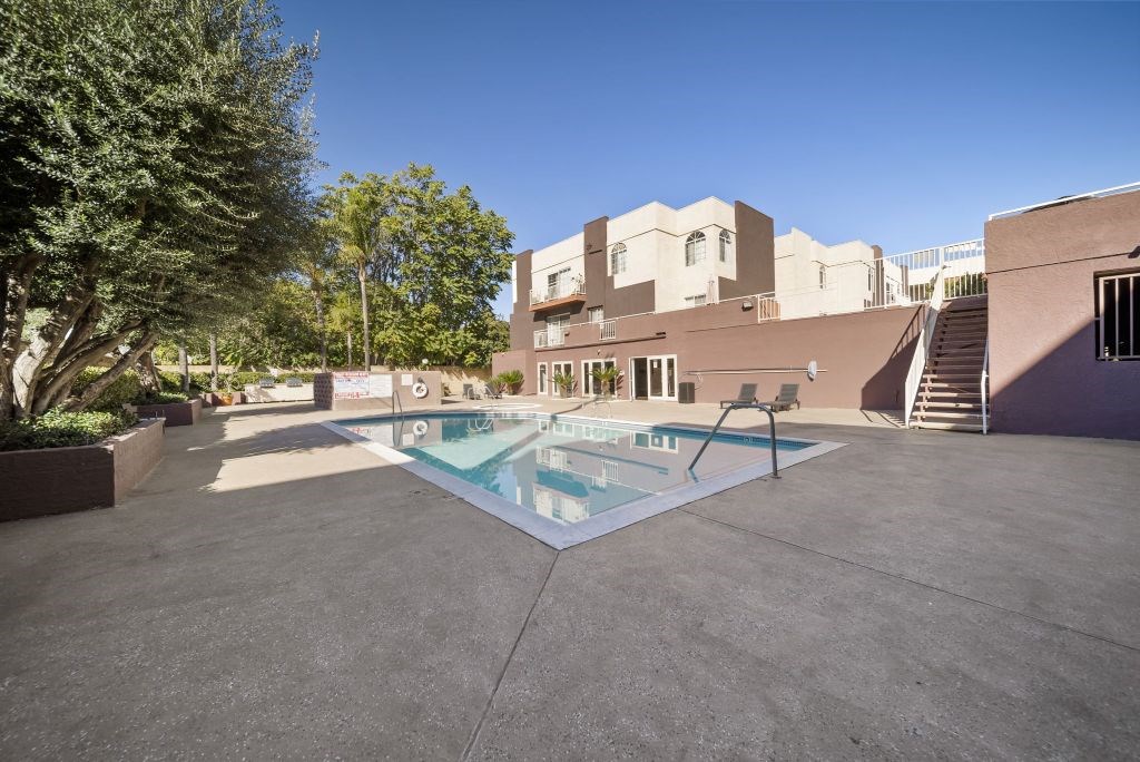 A pool in a courtyard surrounded by trees and buildings.