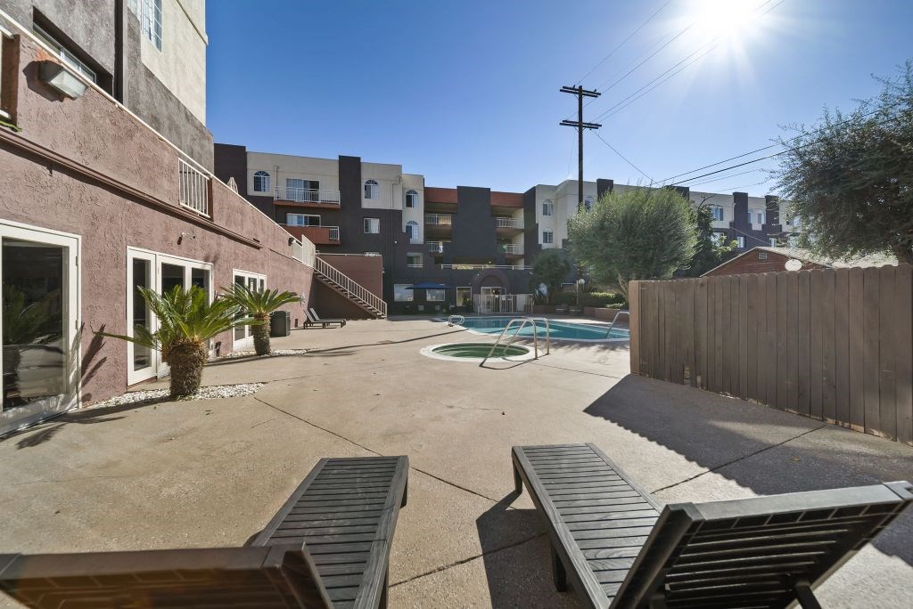 A sunny day in a courtyard with a pool, benches and buildings in the background.
