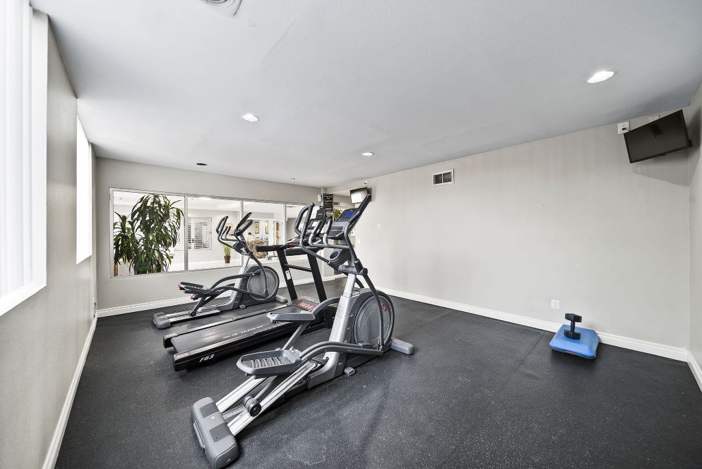 A room with a treadmill, exercise bike, and weights.