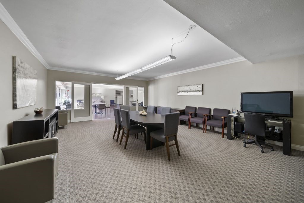 A room with a grey carpet and a black television.