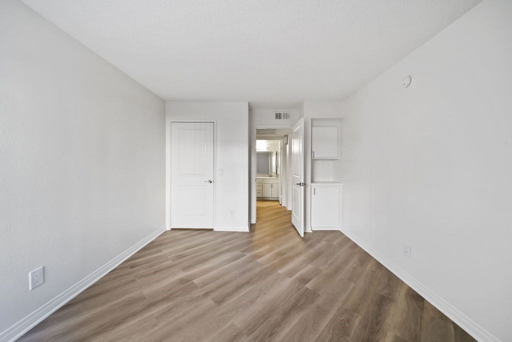 A long hallway with white walls and wood floors.