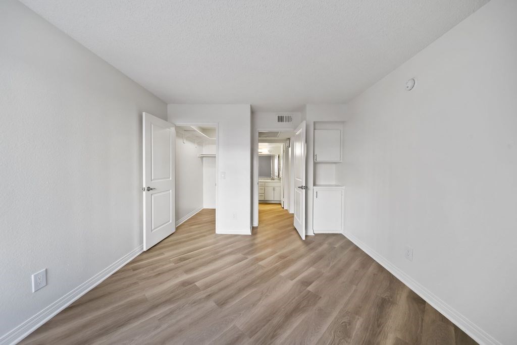 A long hallway with white walls and wood flooring.