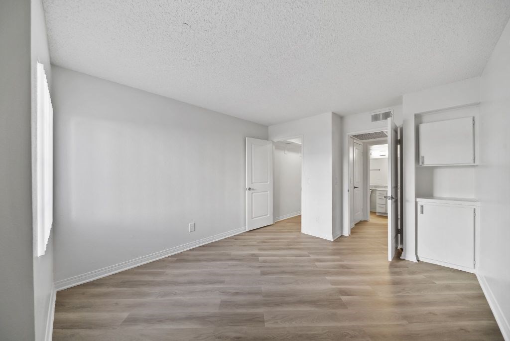 A long, empty hallway with white walls and wood flooring.