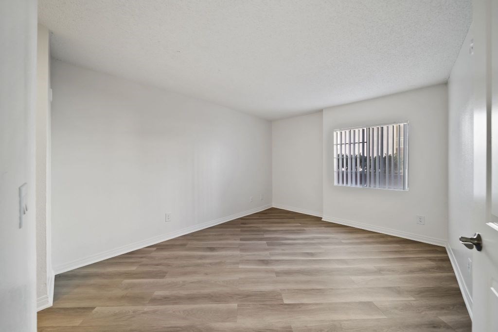 A room with wooden flooring and a window with blinds.