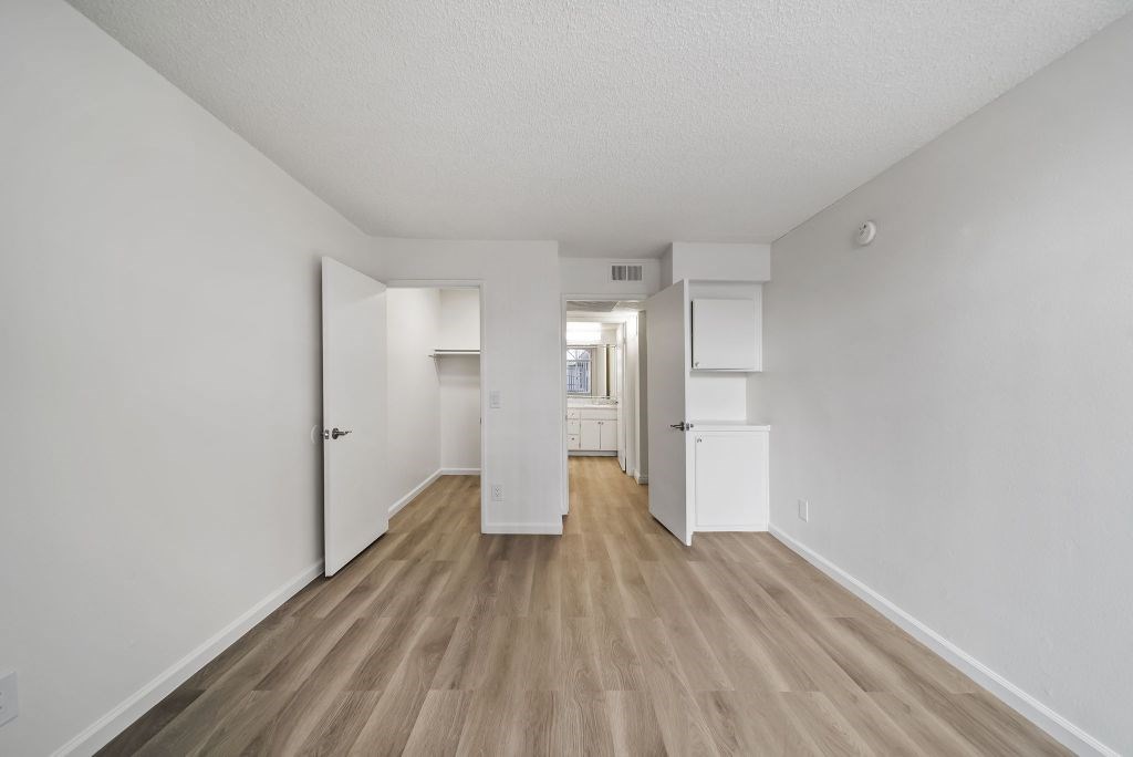 A long hallway with white walls and wood flooring.