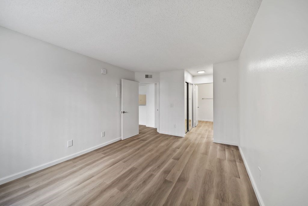 A long hallway with white walls and wood flooring.