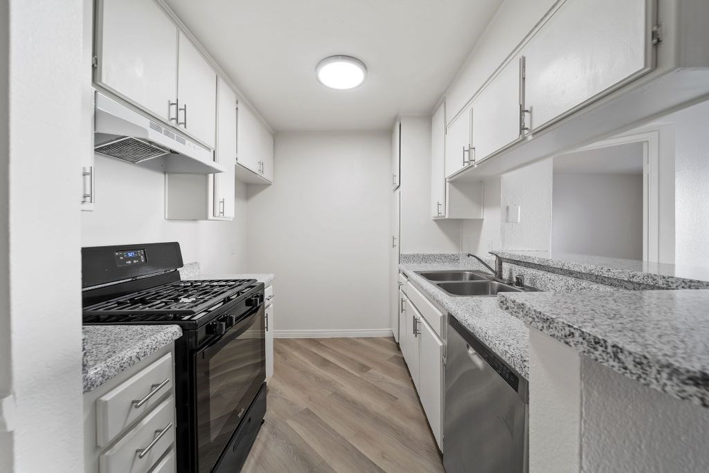 A modern kitchen with a black stove top oven and a granite counter top.