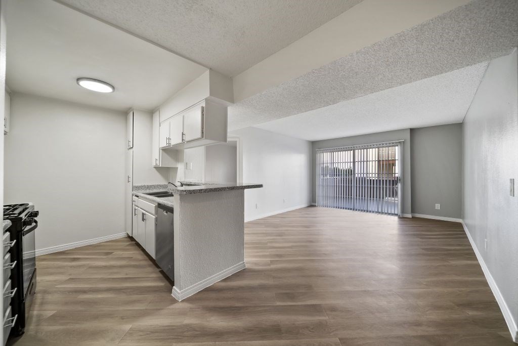 A kitchen with a white countertop and wooden floors.