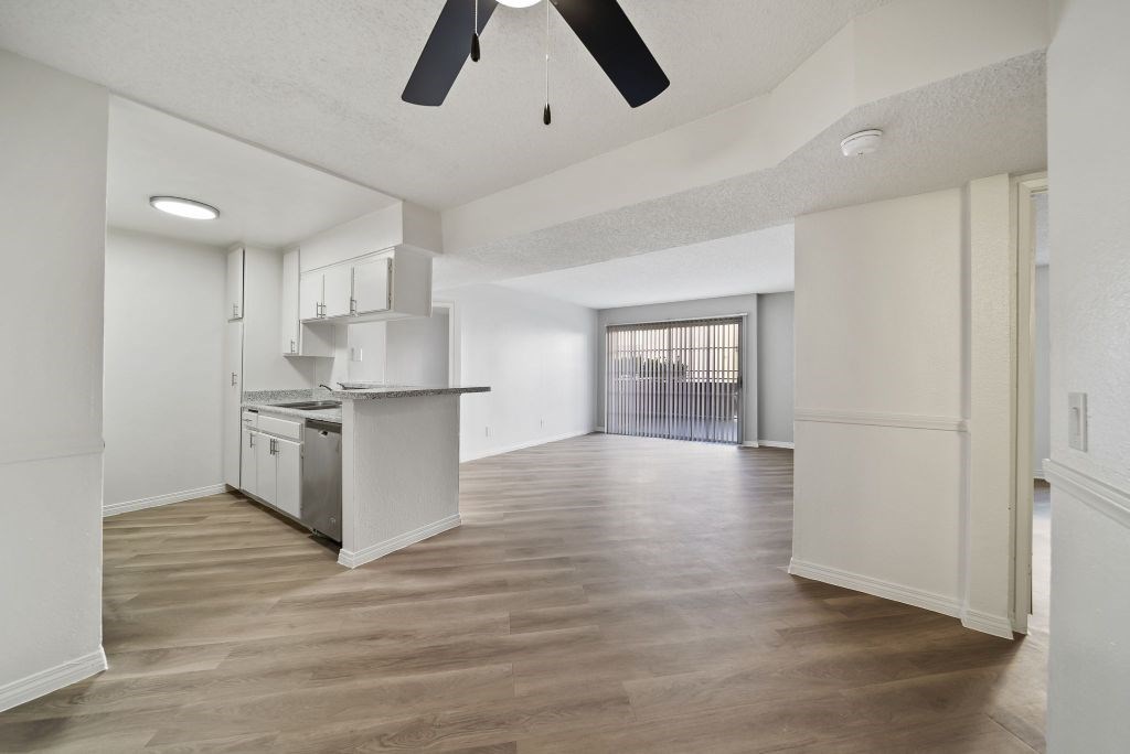 A spacious kitchen with a ceiling fan and wooden flooring.