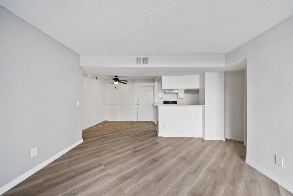 A room with a ceiling fan and a kitchenette.