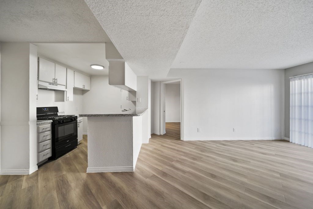 A kitchen with a black stove top oven and wooden floors.