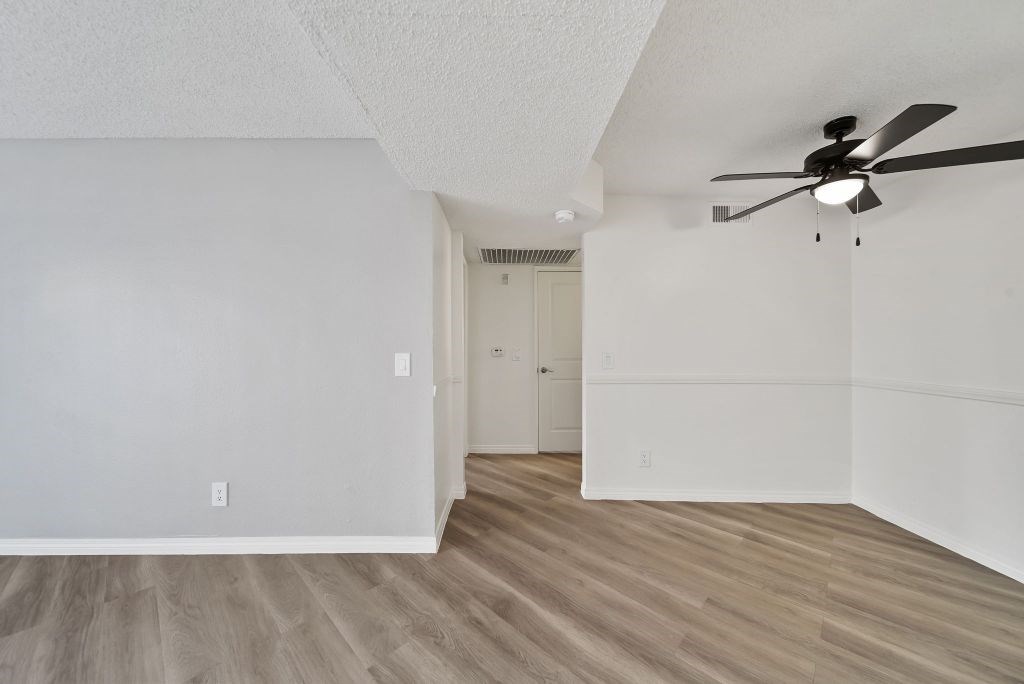 A room with a ceiling fan and light, and a door in the background.