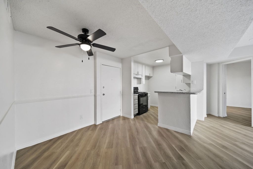 A room with a ceiling fan and wooden flooring.