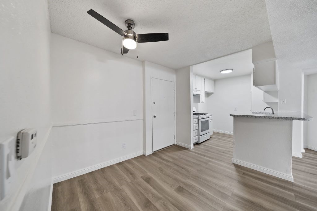 A kitchen with a ceiling fan and wooden floors.