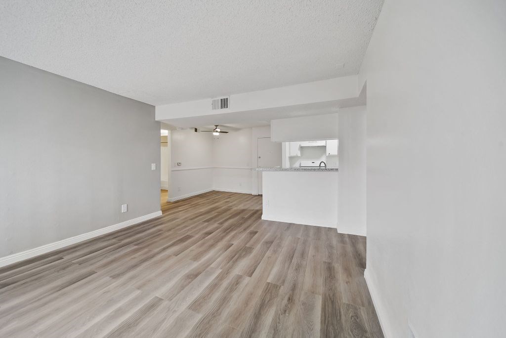 A room with wooden flooring and white walls.