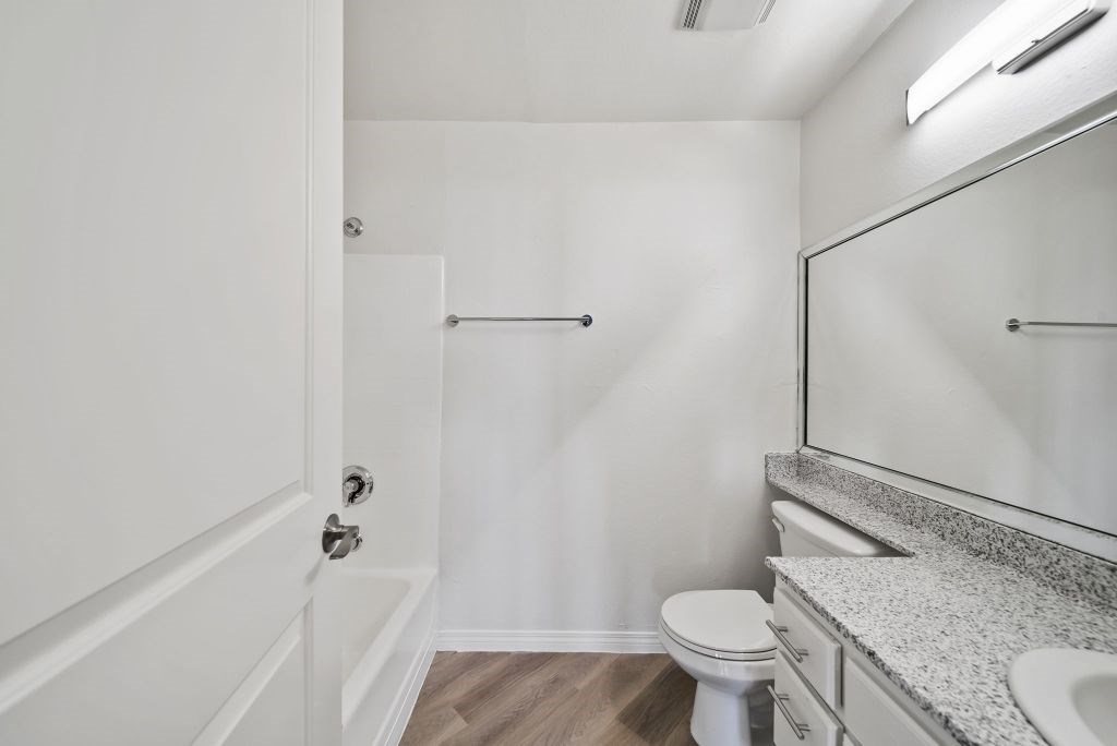 A white bathroom with a toilet, sink, and mirror.