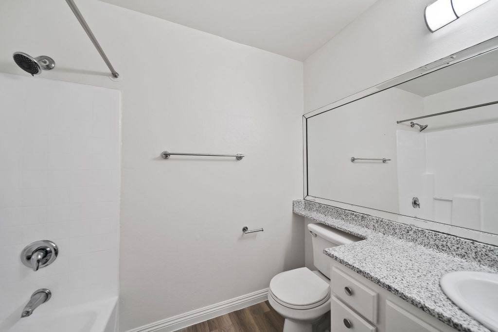 A white bathroom with a toilet, sink, and shower.