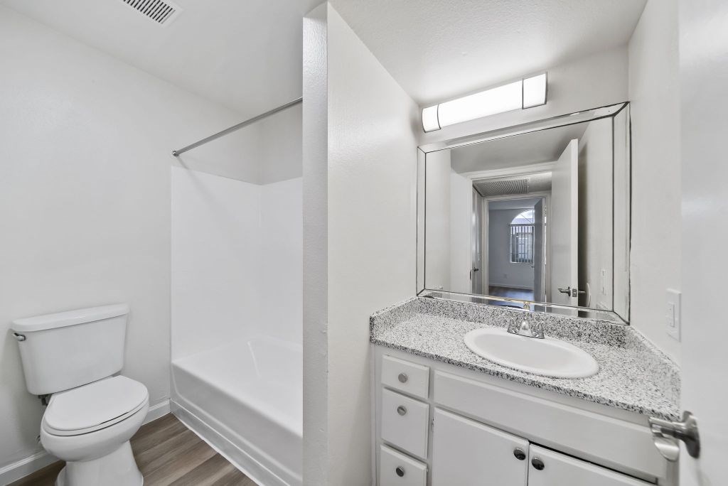 A white bathroom with a toilet, sink, and mirror.