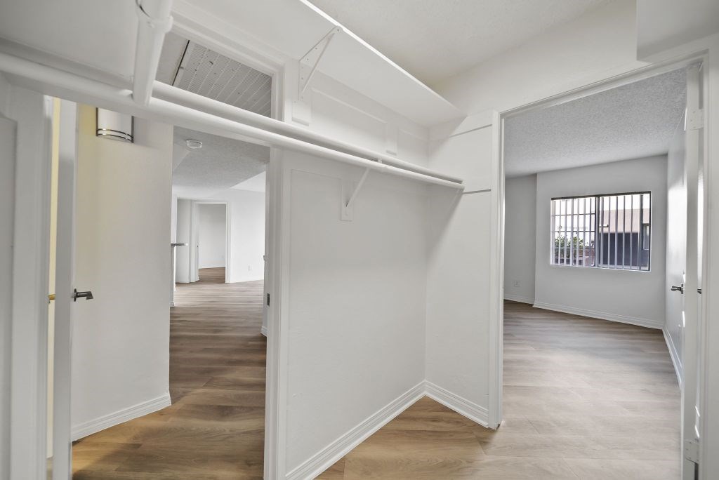 A white room with a door on the left and a window with bars on the right.