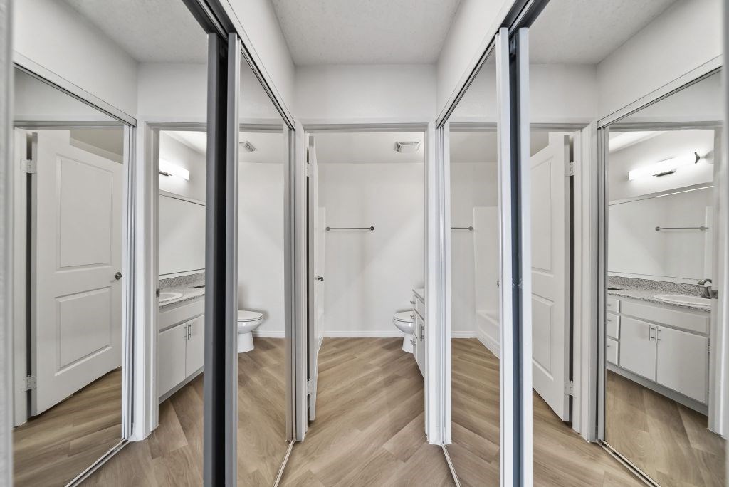 A bathroom with a toilet, sink, and mirrors.