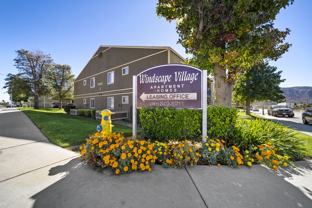 A sign for Windsafe Village Apartment is in front of a building.