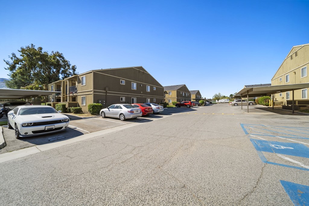 A parking lot with cars and apartment buildings in the background.
