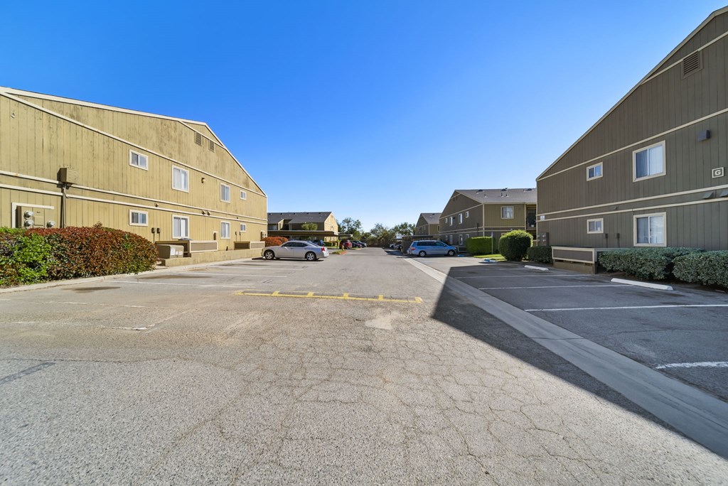 A parking lot in front of a building with a car parked in the distance.
