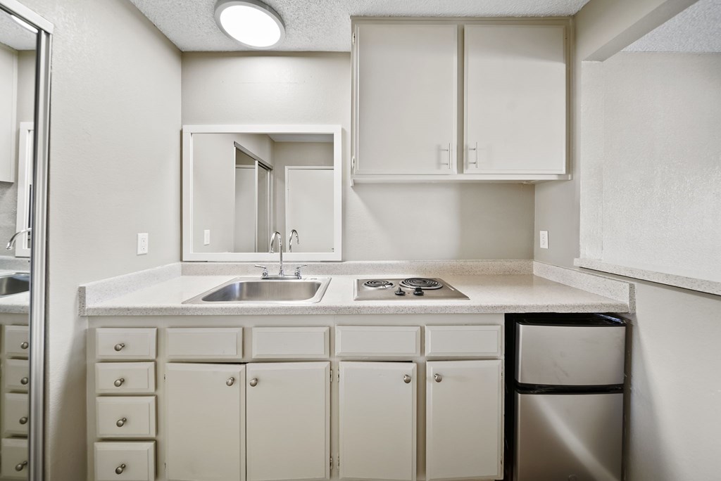 A white kitchen with a sink and a trash can.